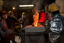 Pouring molten bronze into a mold.